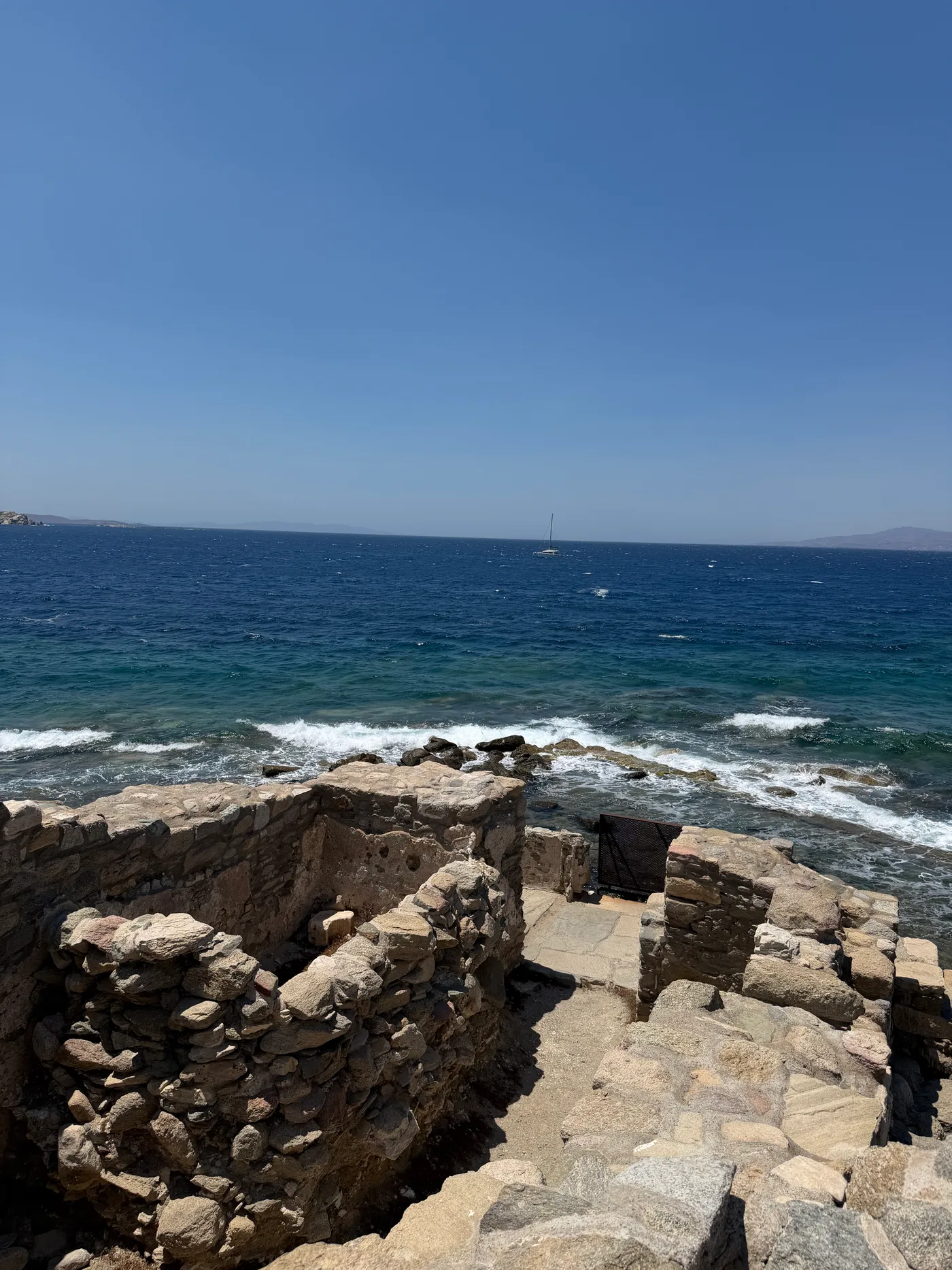 Old stone walls on a rocky shore above a deep blue sea